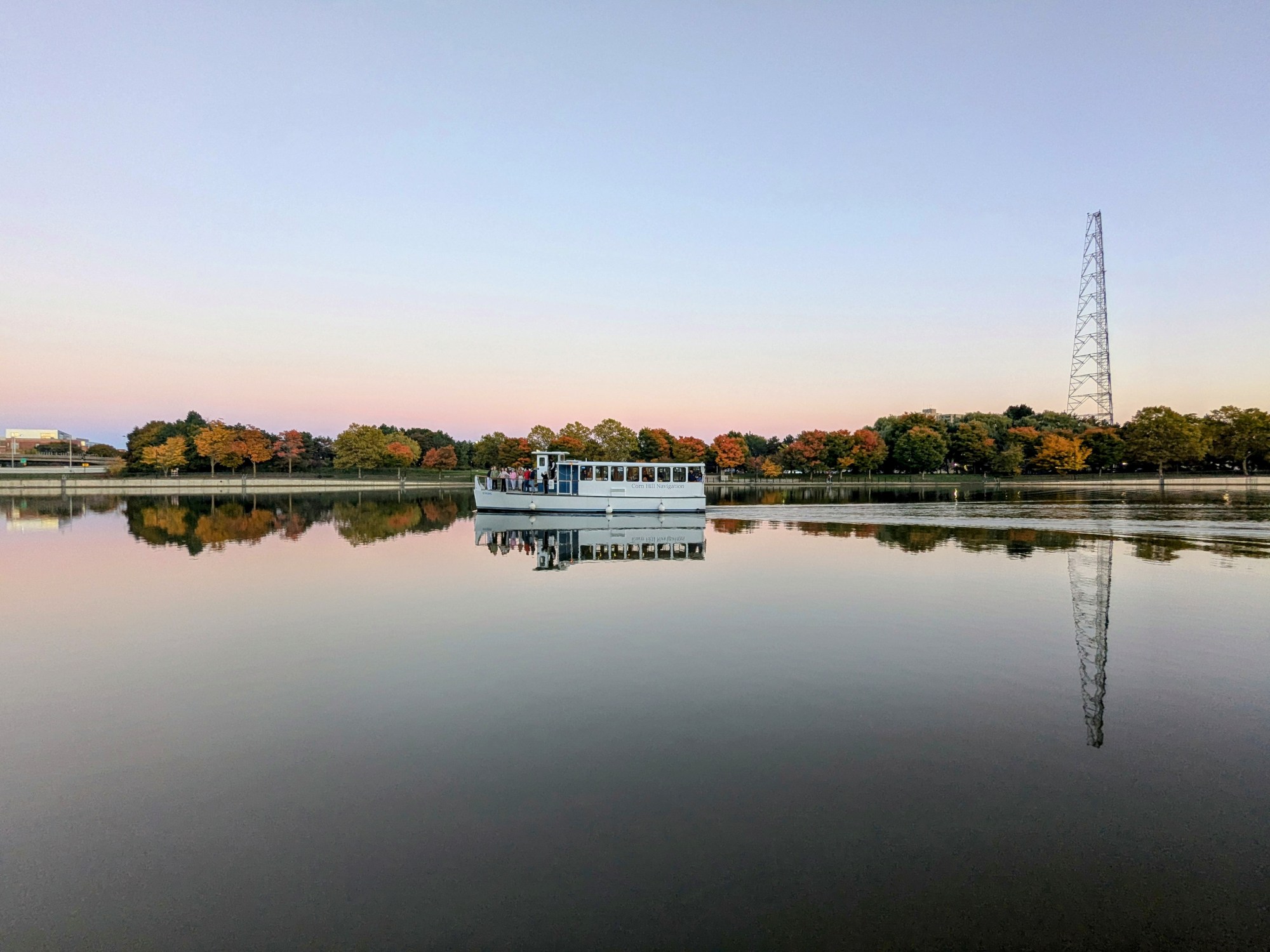 PXL_20241019_222459292.MP~2 a boat traveling on the glassy water during fall foliage
